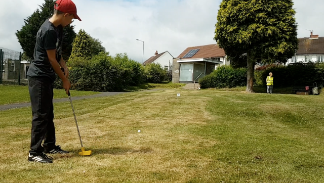 A young golfer takes a shot at the putting green in Old Cwmbran