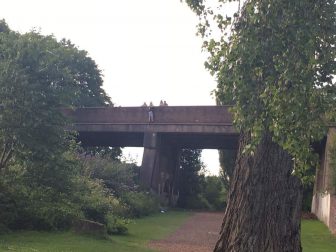 A boy walking along the edge of the bridge over the railway track in Llanyrafon
