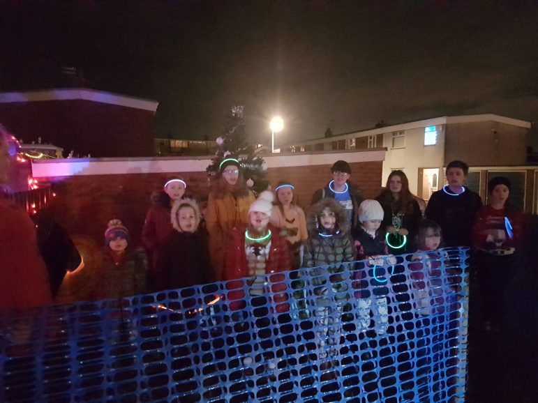 Thirteen young residents singing Christmas carols in Northville