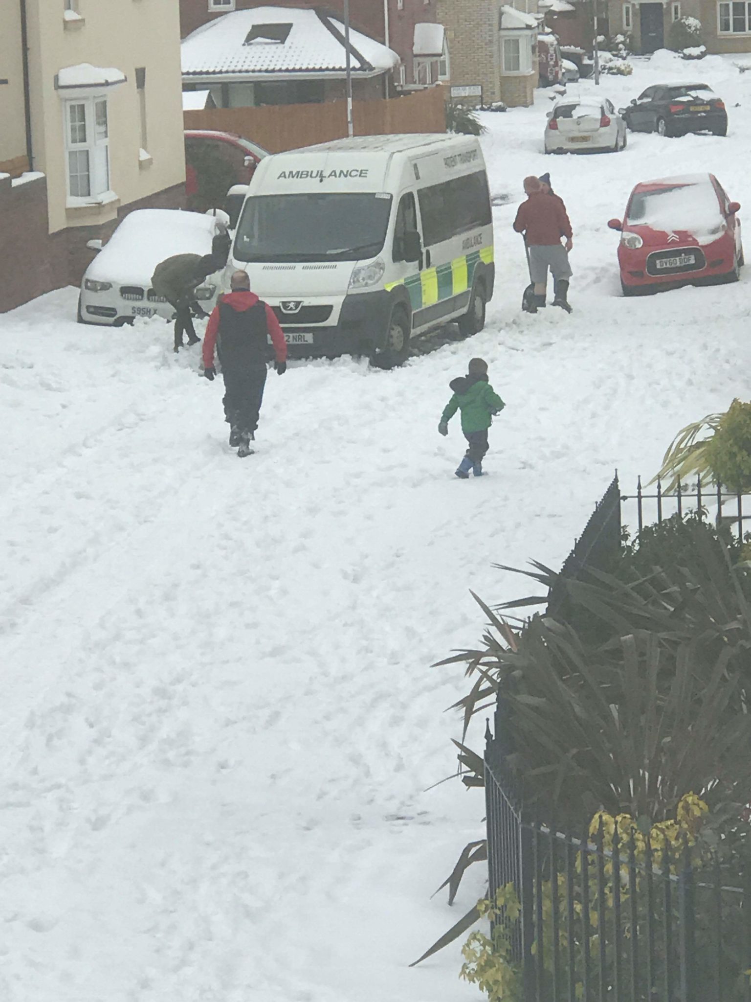 Resident clear a road of snow for an ambulance in Cwmbran