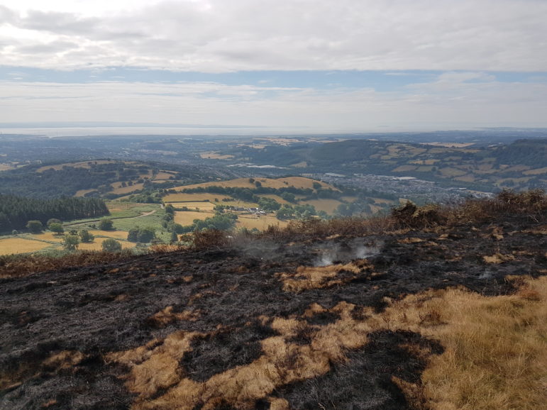 Smouldering grass on the slopes of Twmbarlwm