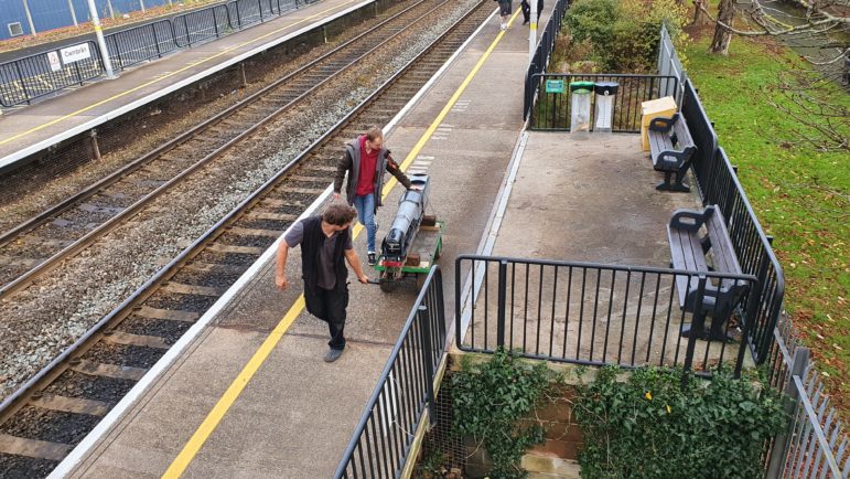 Two men wheeling a train on a trolley