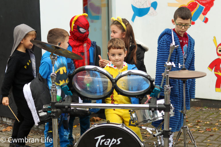 A boy plays the drums with children behind him