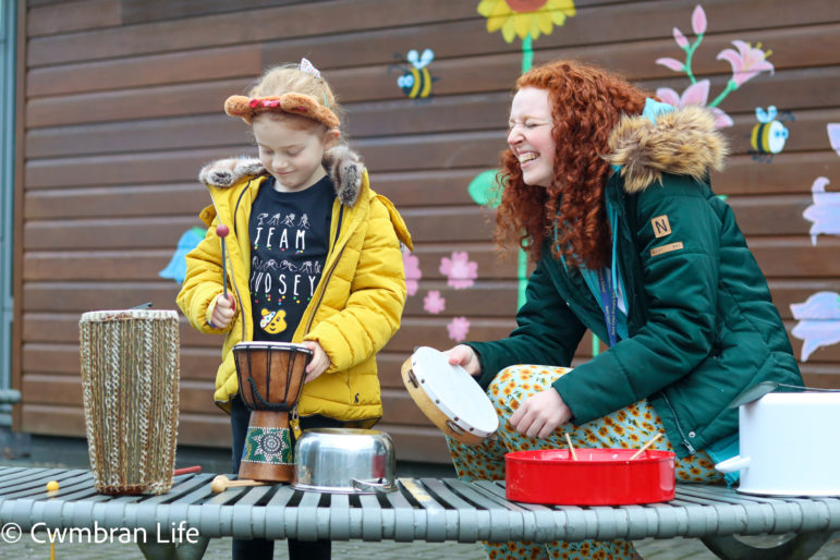 A girl plays the drums with a woman