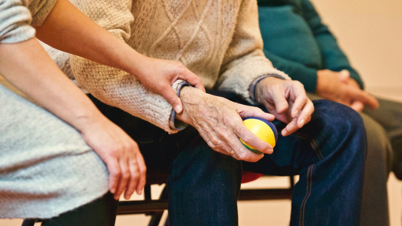 A carer holds a man's hand