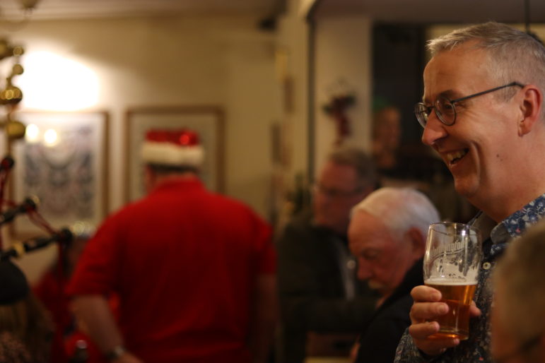 a man holding a pint and laughing