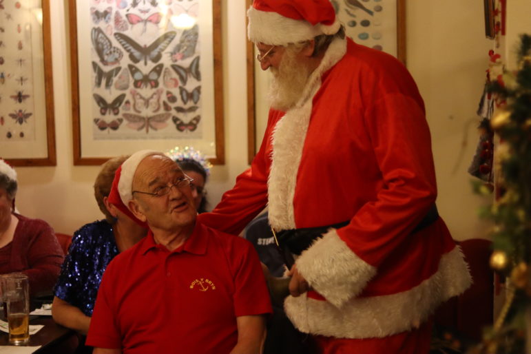 man dressed as santa talks to man