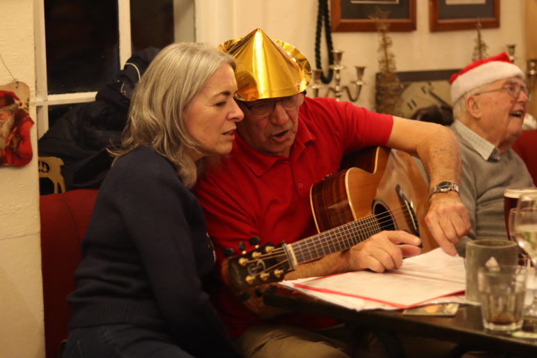 a man and woman looking at song sheet in pub