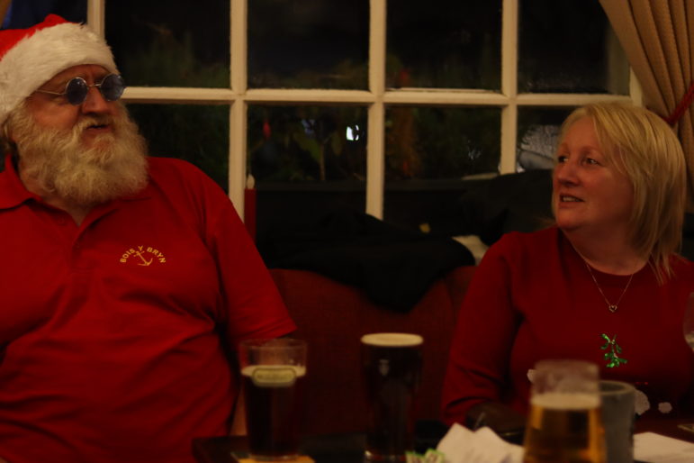 a man in santa hat sat with a woman in pub