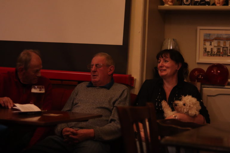 A woman holding a dog sat next to two men