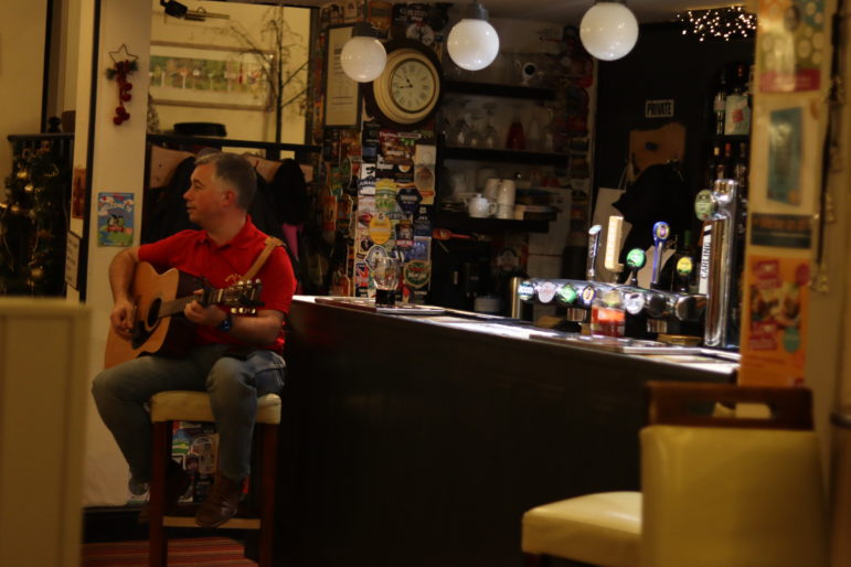 a man sat at bar with a guitar