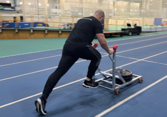 Richard Selby pushes a sled on a running track