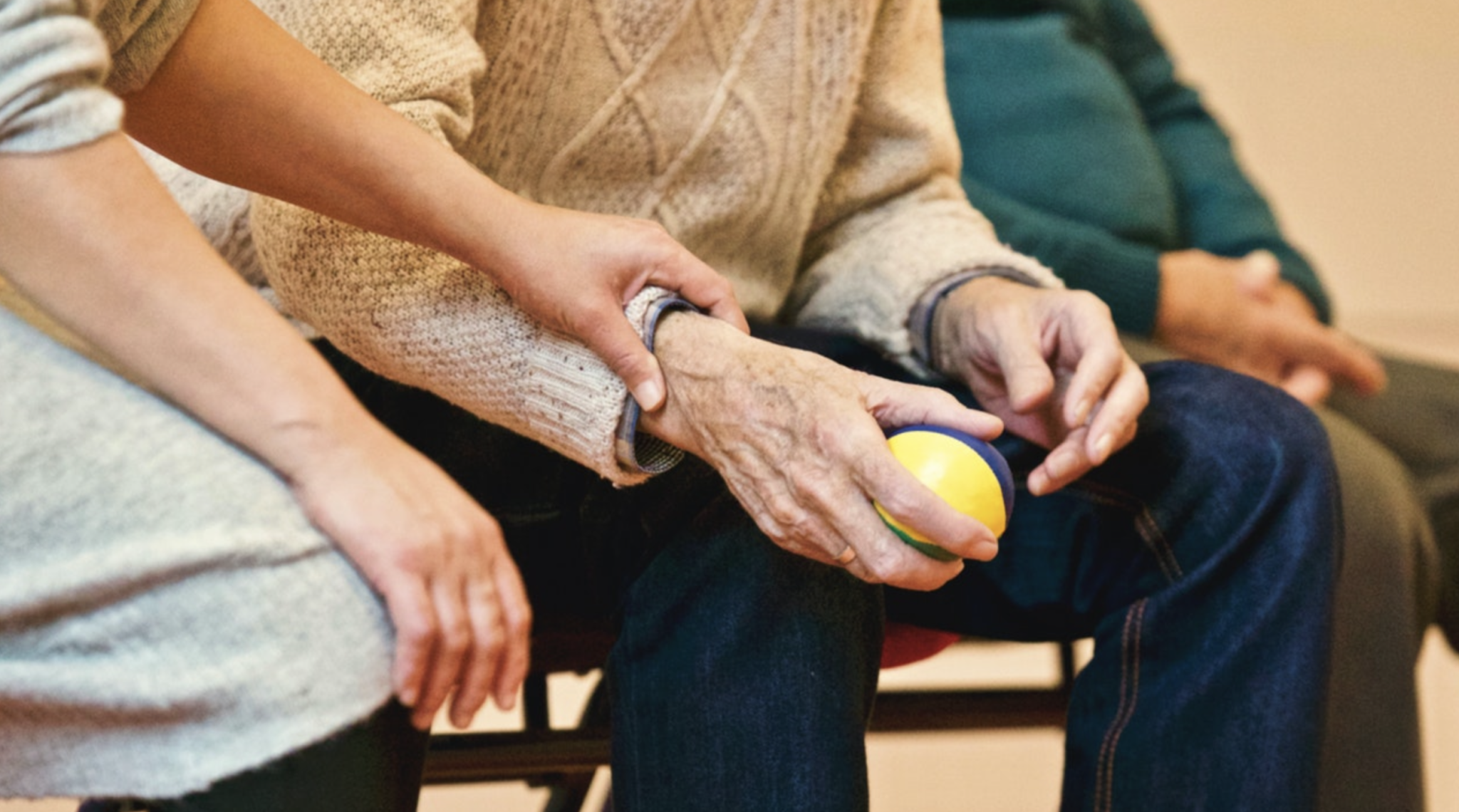 a carer carefully holding an older person's hand
