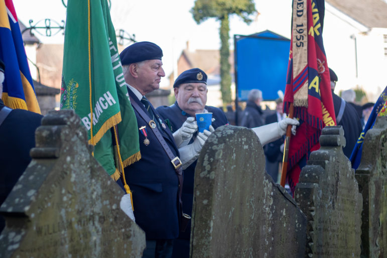 two men holding flags at a grave