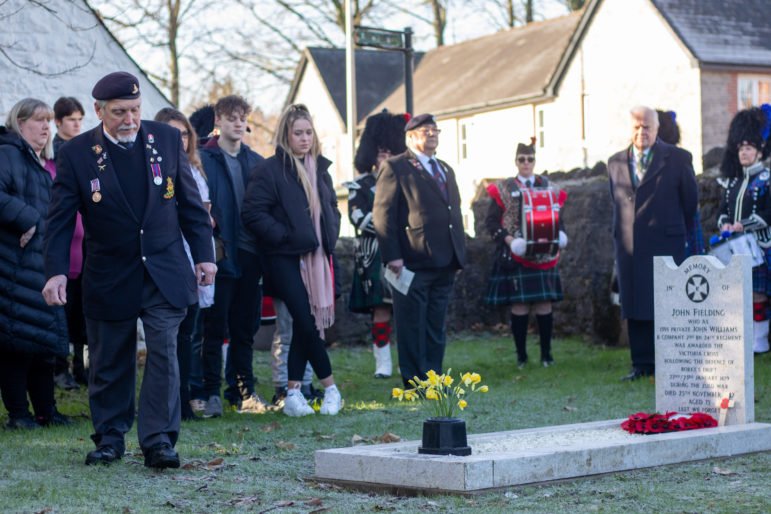 A former serviceman walks towards a grave