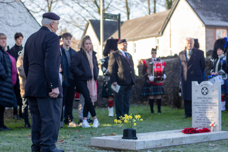 A former service man about to salute in front of a grave