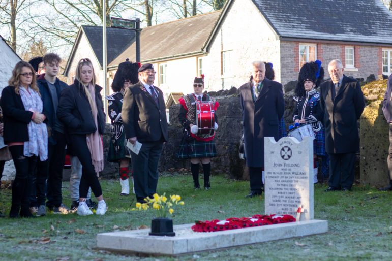People at remembrance service around a grave