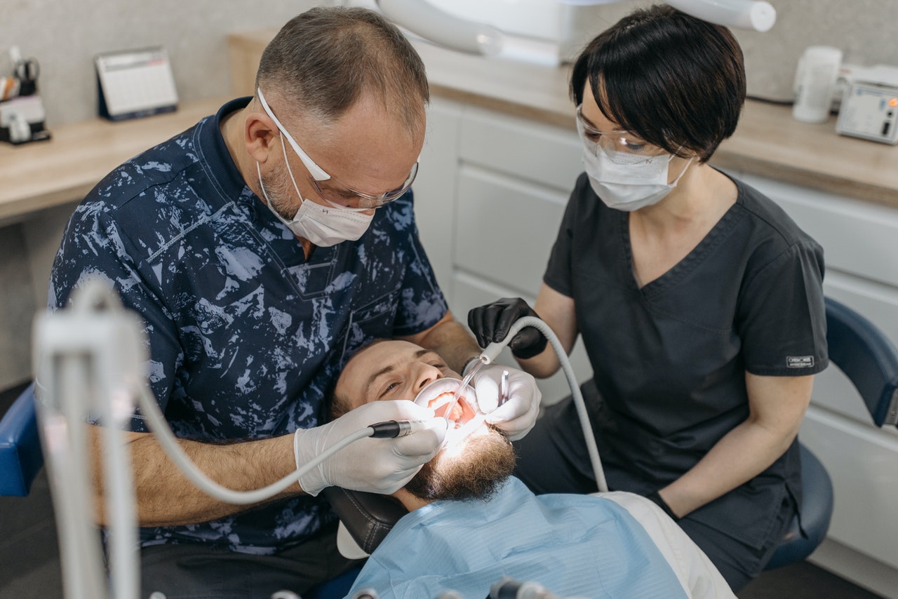 A Dentist and His Dental Assistant Working on a Patient