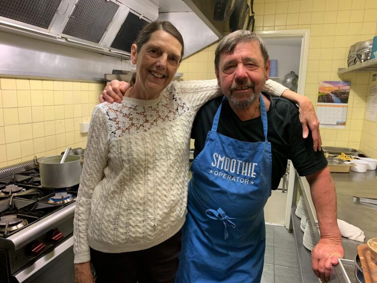 Couple stood in pub kitchen with arms around each other