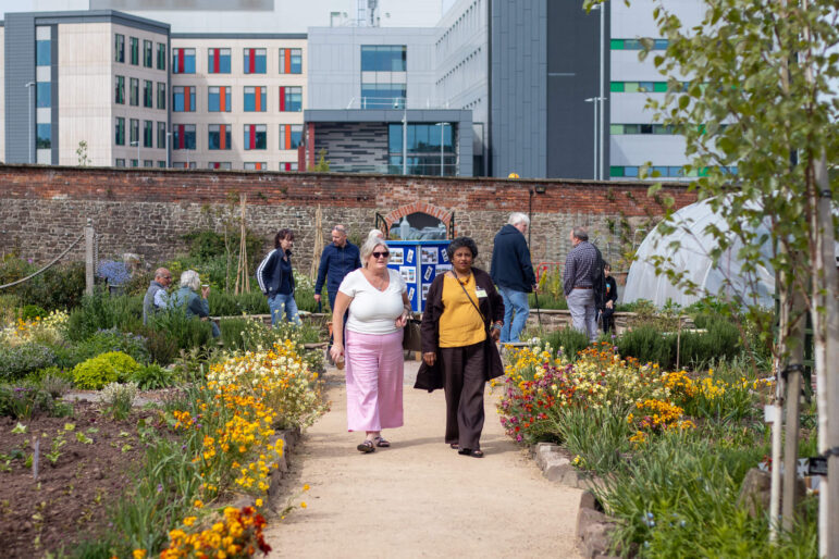 two women walk through a garden