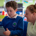 a boy looked at ipad watched by woman