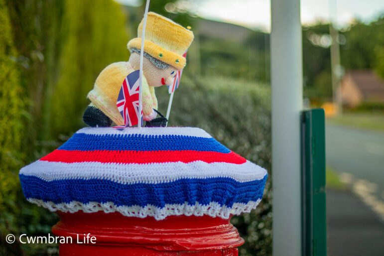 A knitted Queen on top of postbox on
