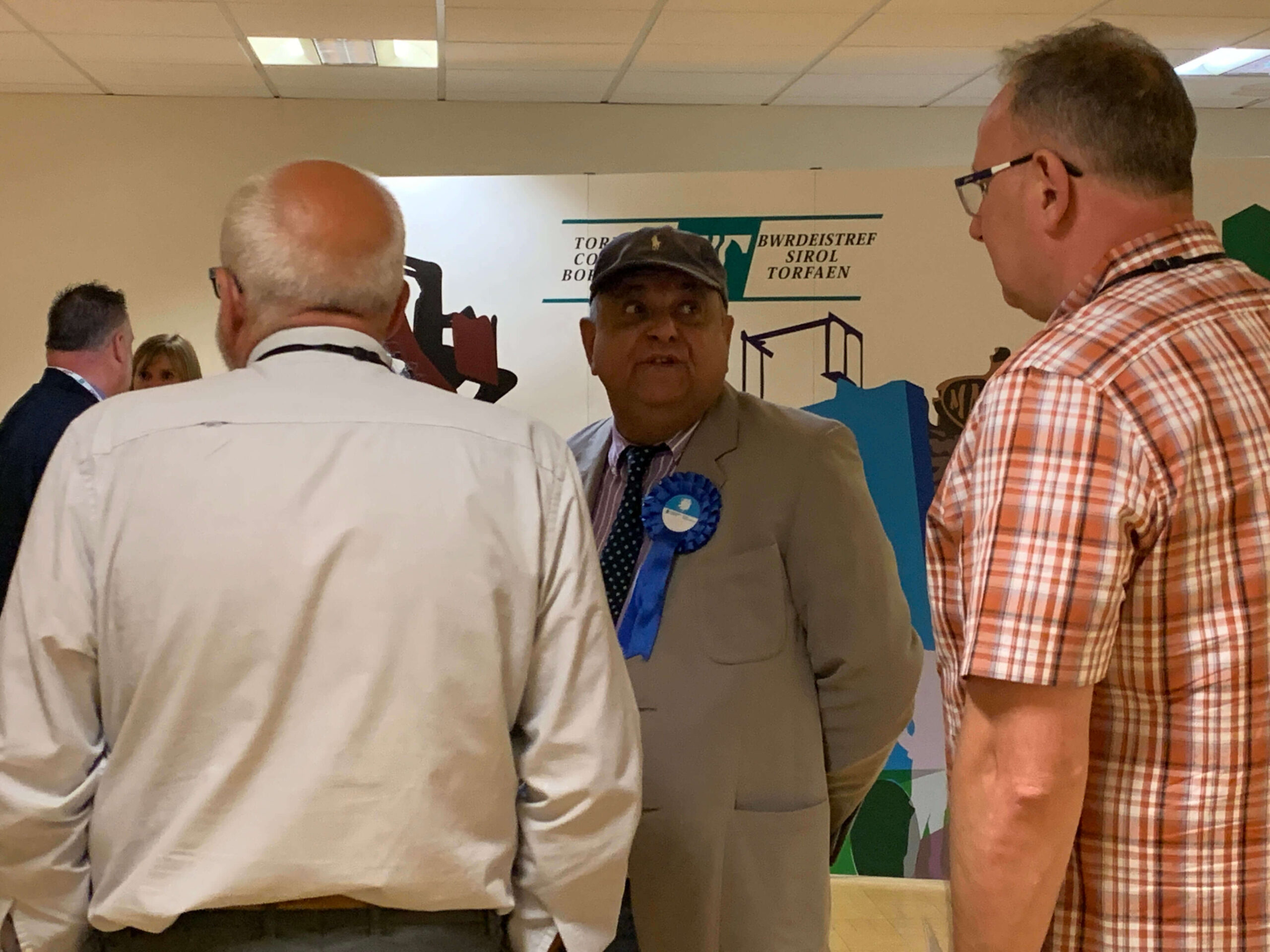 a man wearing a blue rosette