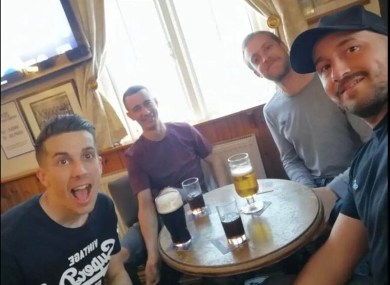 four men with beers in a pub