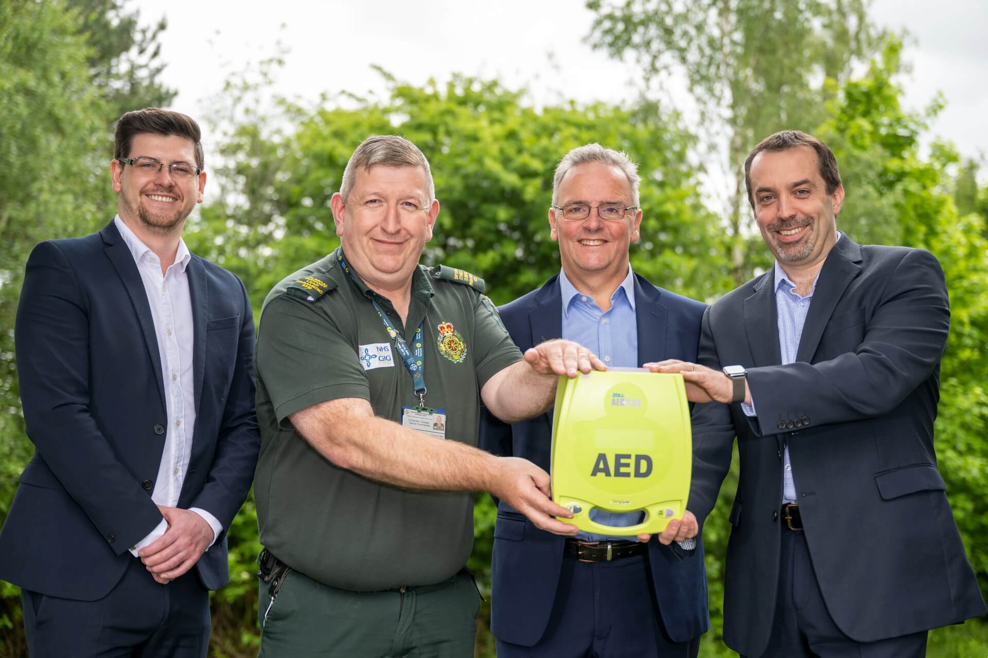 four men hold a defibrillator