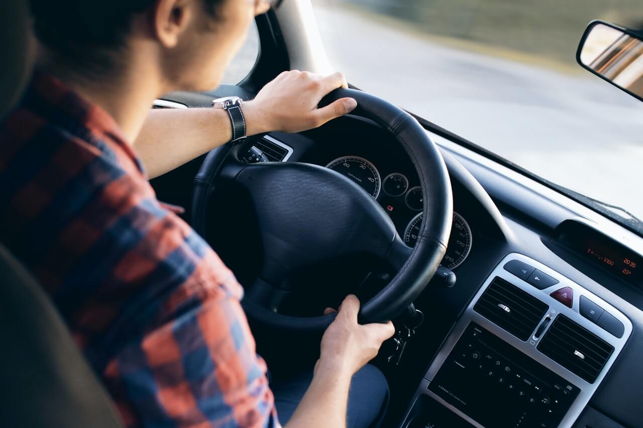 a man with hands on steering wheel