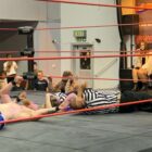 two wrestling referees lay on the floor of a ring