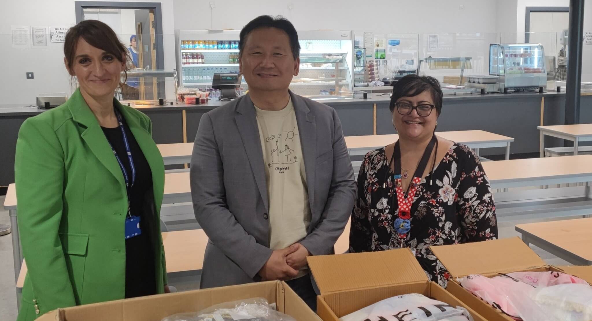 three people stood by boxes of knitted items