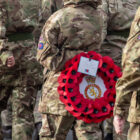 an army cadet holding wreath of poppies