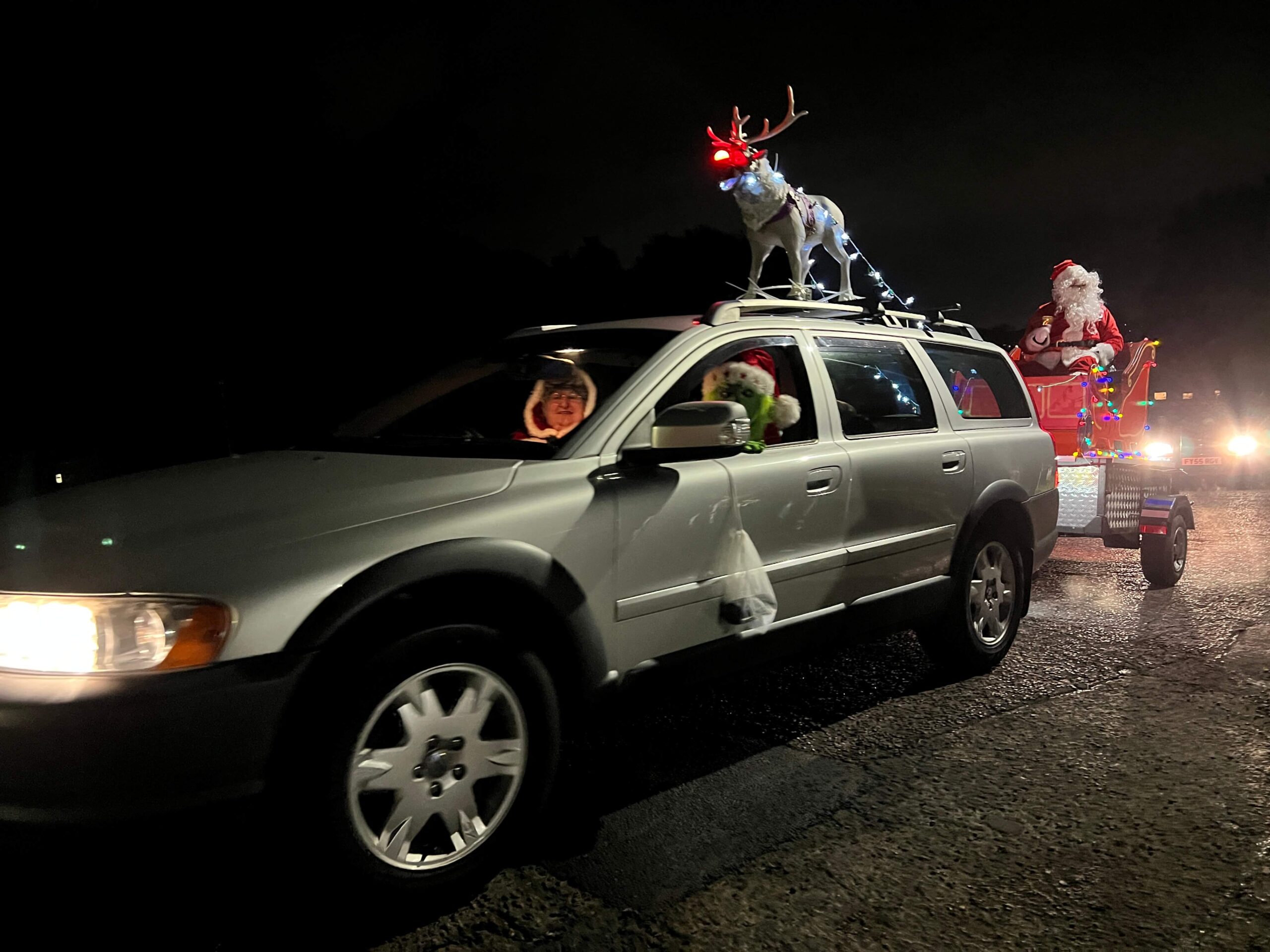 Santa being towed on a sleigh behind a car
