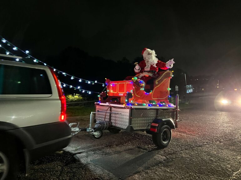 Santa on a trailer behind a car