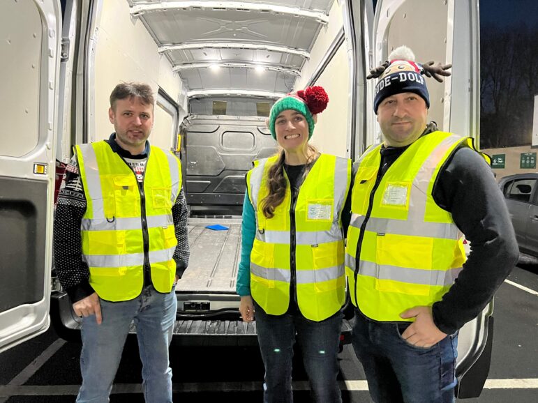 three people stood by a transit van