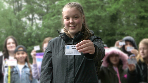 a young carer holds up her ID card