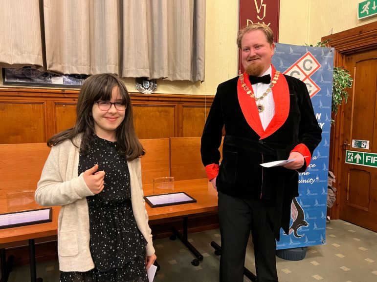 a girl is presented with a certificate by a chairman of a council