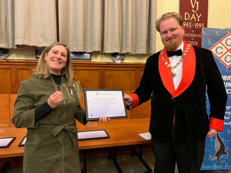 a woman collects a certificate from the chairman of a council