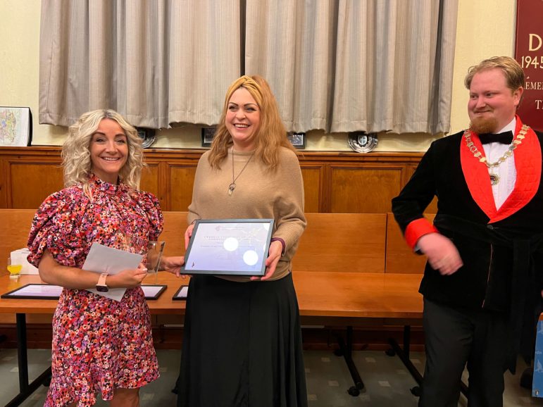 a woman is given a certificate from a councillor