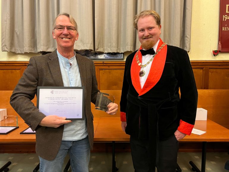 a man collects a certificate from a chairman of a council