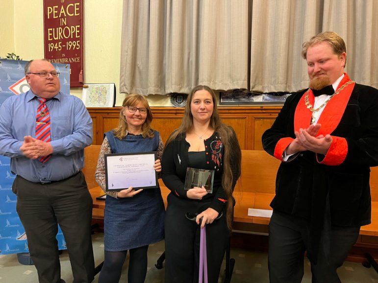 two women collect an award from two councillors