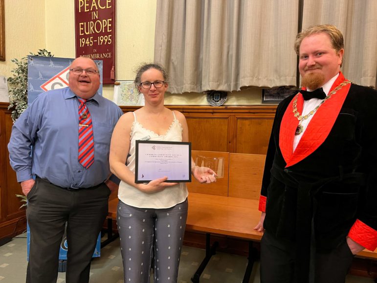 a woman collects an award from two councillors