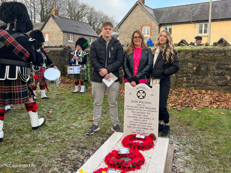 a mum and two adult children stood by a grave