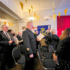 People in a room stand to sing a hymn