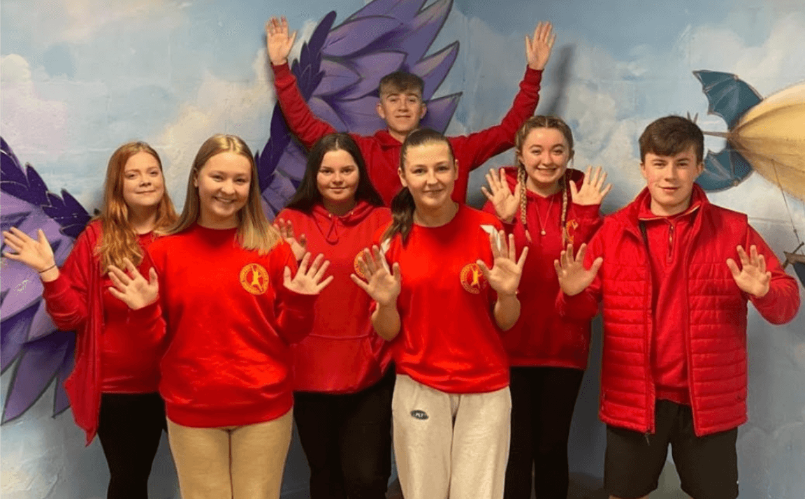 a group of play workers give the 'thumbs up' to the camera