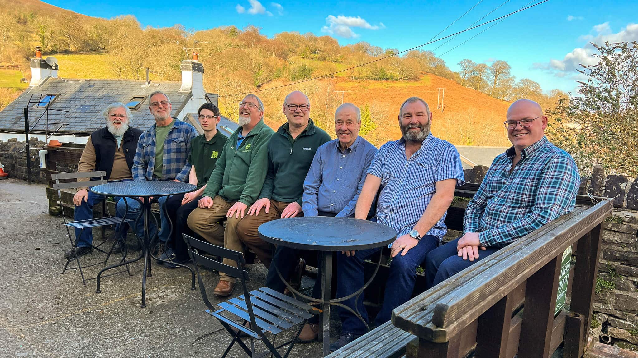 a group of people sat on a bench outside a pub