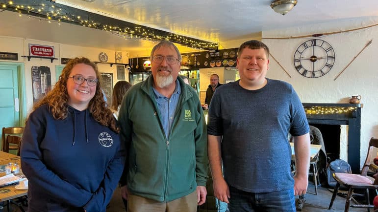 two men and a woman standing in a pub