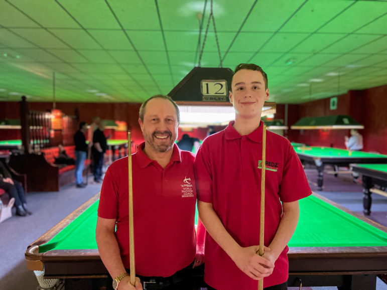 two snooker players stood by a table