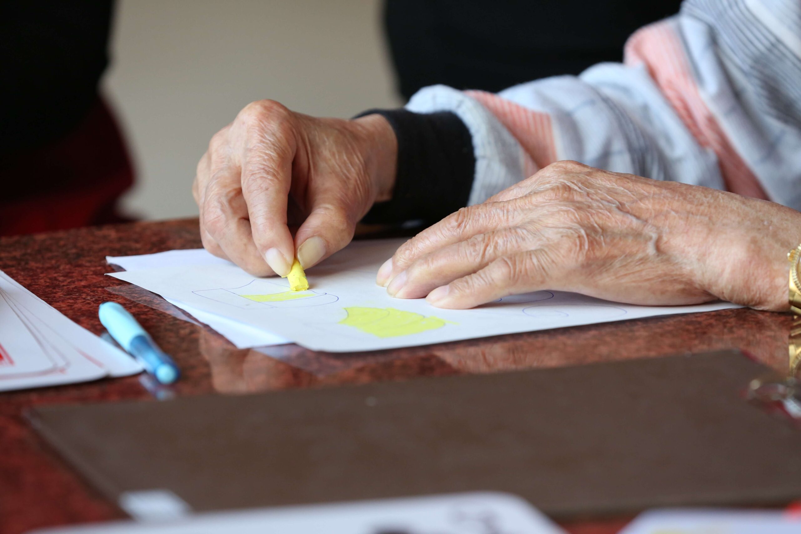 an older person draws with crayons